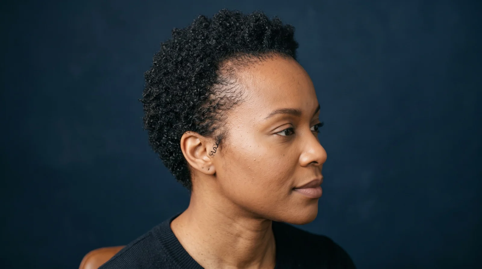 Three-quarter view highlighting natural coily hair direction at the temple