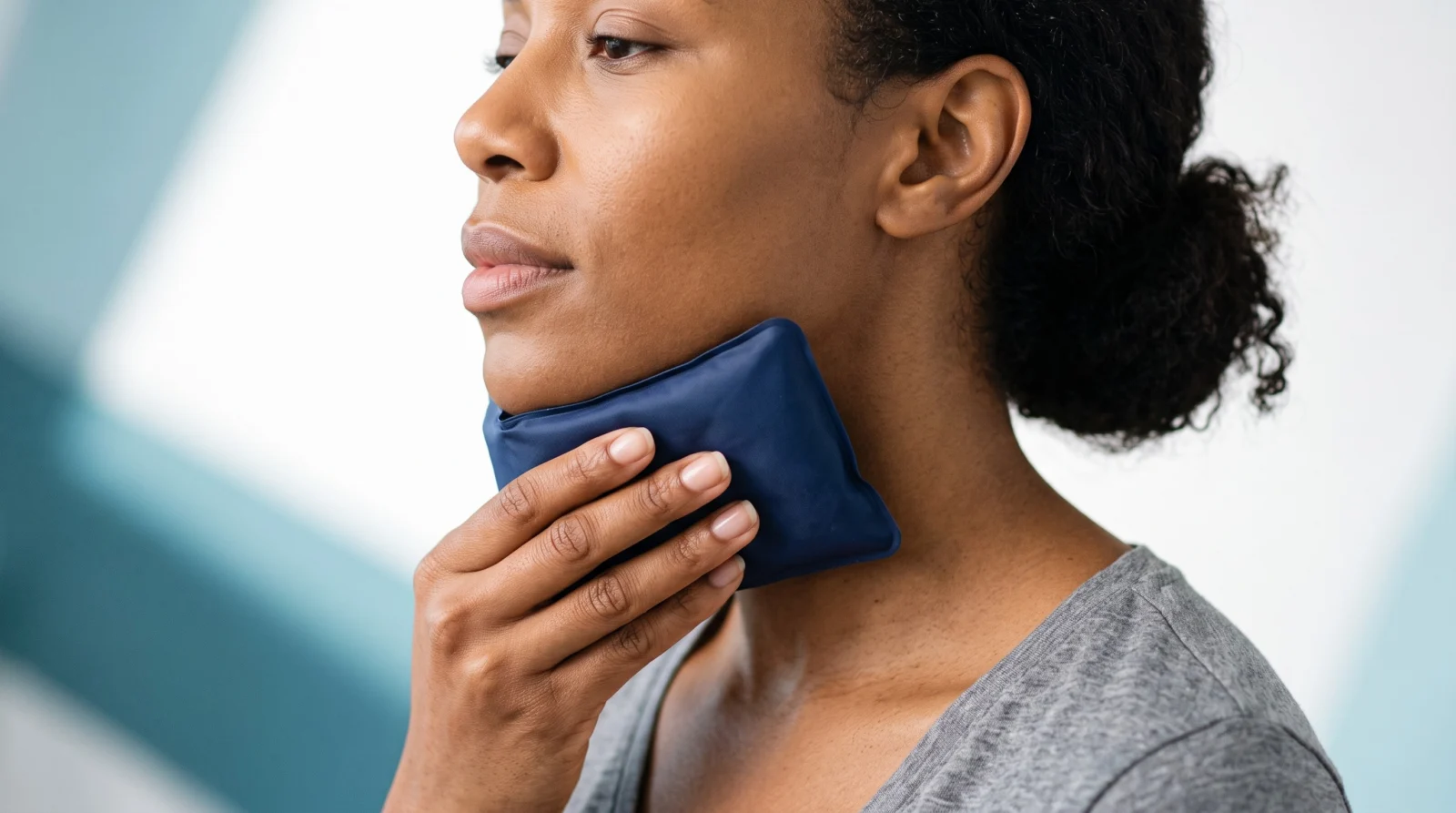 Woman holding a plain cold pack beneath her chin during early recovery